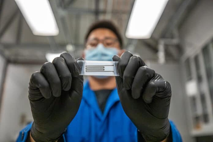 Junpyo Kwon, a Ph.D. student researcher from the Xu Group at UC Berkeley, is shown holding a recyclable, biodegradable printed circuit.