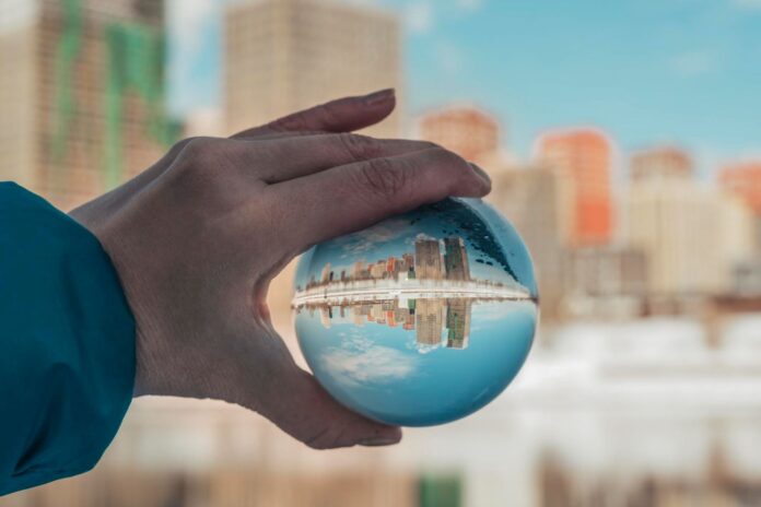 Close-up of hand holding crystal ball against built structure