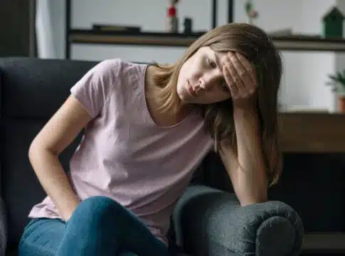 Unhappy young woman sitting on armchair