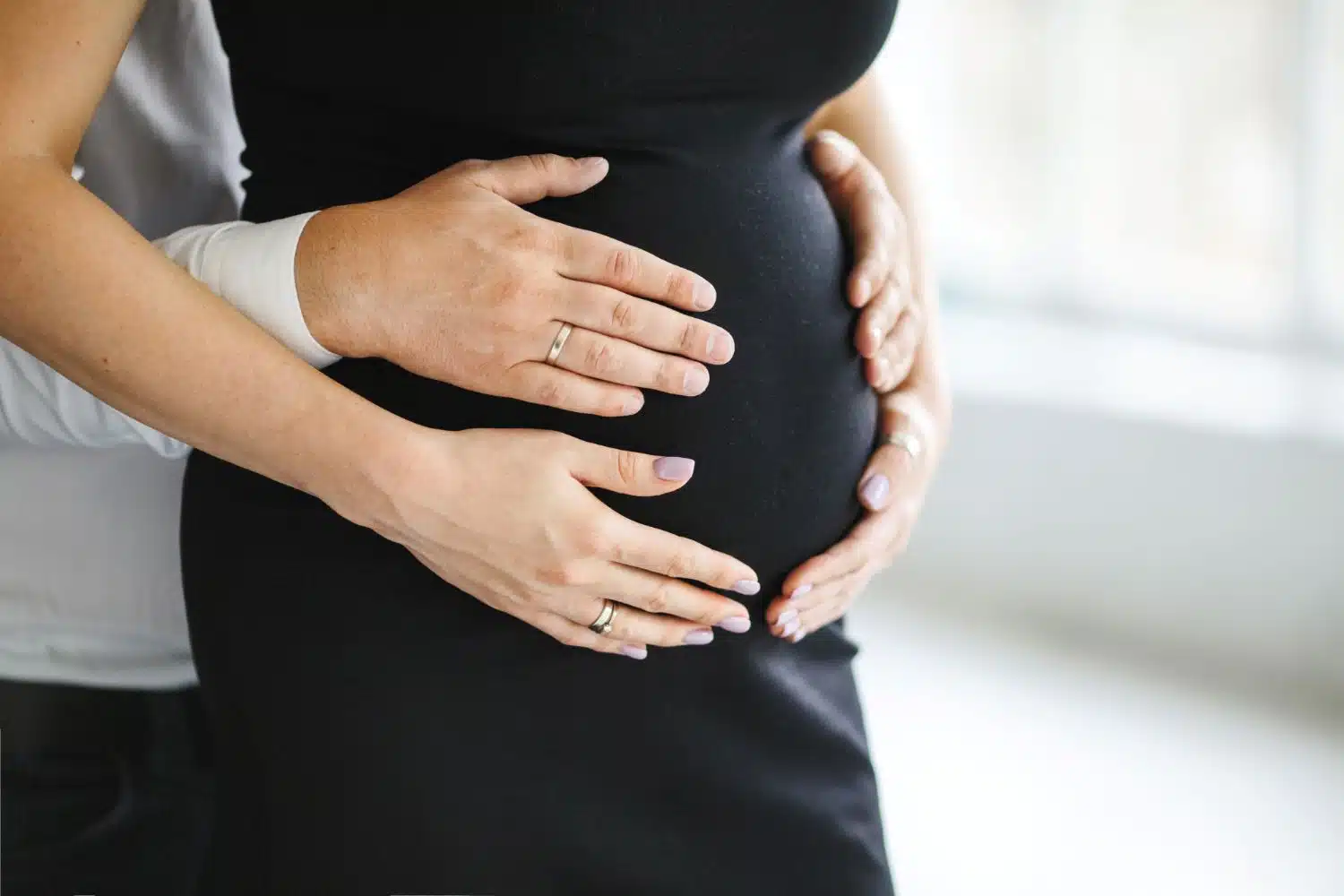 Man holds hands for her pregnant wife belly