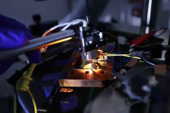 To measure the power produced by his photovoltaic cells, Roy-Layinde holds a heat source held over the photovoltaic cell, which emits the infrared radiation that the cell converts into electricity. Wires connected to the photovoltaic cell run the electricity to a sensor that reads the voltage and amperage.