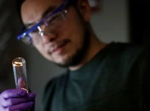 Jun Lu examines the twisted filament glowing within the bulb. He, along with a team of U-M researchers, demonstrated for the first time that a twisted filament could produce twirling light waves